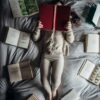 a little girl laying on a bed with lots of books